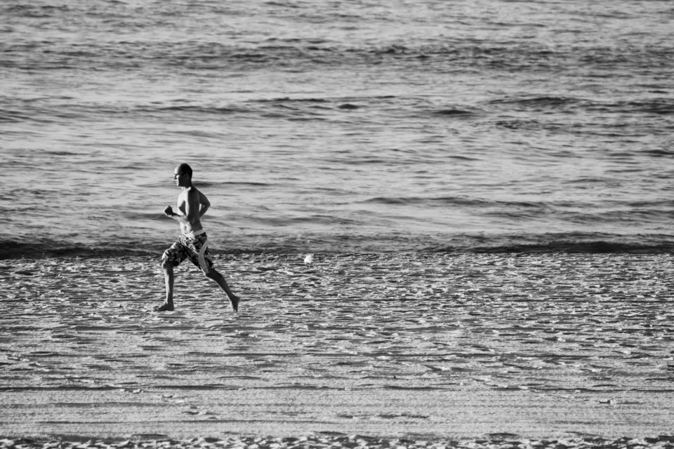 A runner on the beach at the water's edge