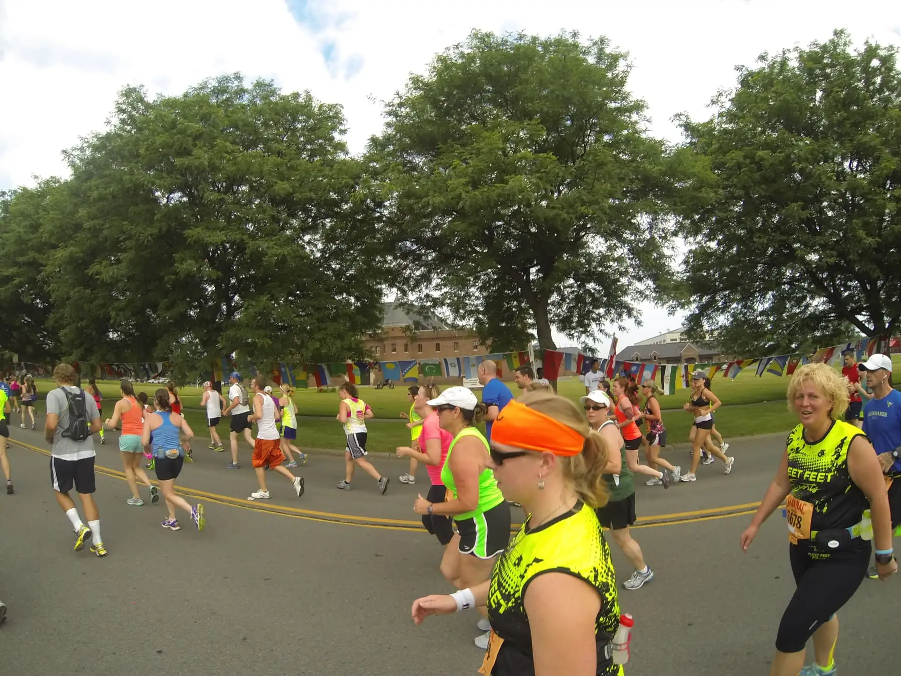 Runners in race bibs on a tree-lined road